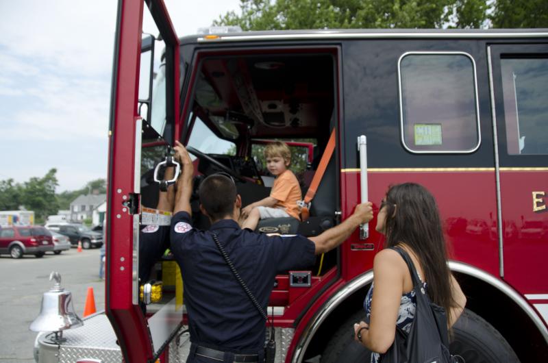 Firefighter Ross Macedo let Hoyt Hottel, IV try out the driver's seat of one of the department's trucks, with Patricia Hottel. BY GEORGIA SPARLING